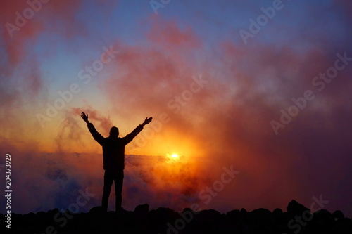 Colorful sunset with a silhouette of a relaxed teenage boy on a long distance hiking trail GR131 leading from Fuencaliente to Tazacorte, La Palma, Canary Islands, Spain