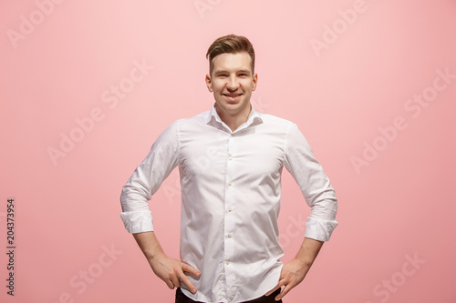 The happy business man standing and smiling against pink background.