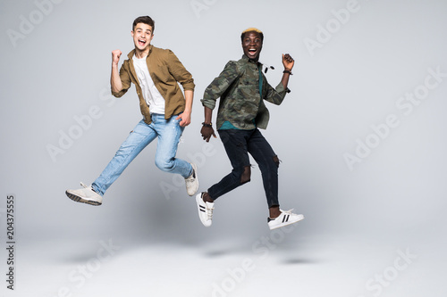 Two mixed race friends student jumping isolated on white background. Multiracial friendship