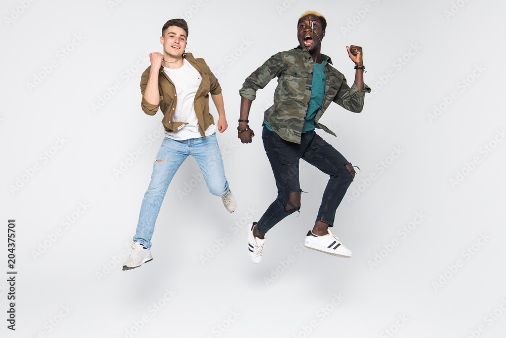 Two mixed race friends student jumping isolated on white background. Multiracial friendship