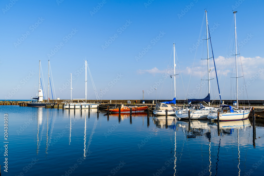 Skanor, Sweden - Windless and tranquil morning in the marina with sailboats and motionless sea. Logos and id removed.