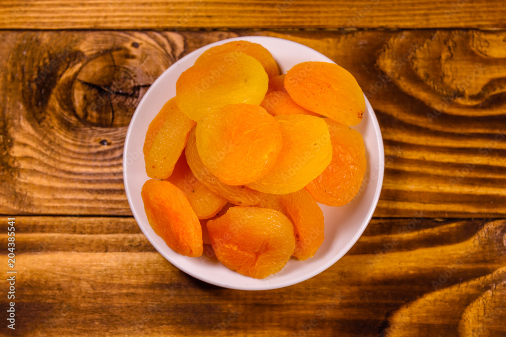 Ceramic plate with dried apricots on wooden table. Top view Ceramic plate with dried apricots on wooden table. Top view