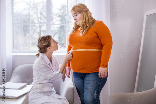 Very bad results. Determined professional nutritionist talking with a fat woman and measuring her