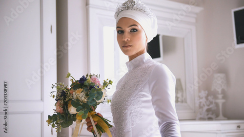 Photography Muslim bride in white wedding dress holding the bouquet of flowers in hand