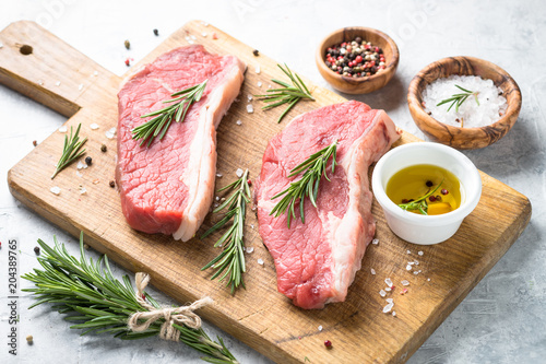 Raw beef striploin steak on cutting board. 