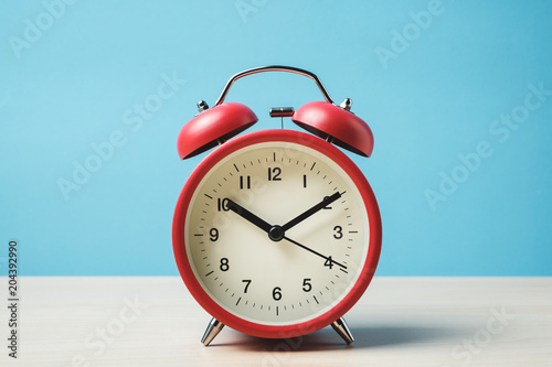 Red vintage alarm clocks on wooden table and light blue background wall