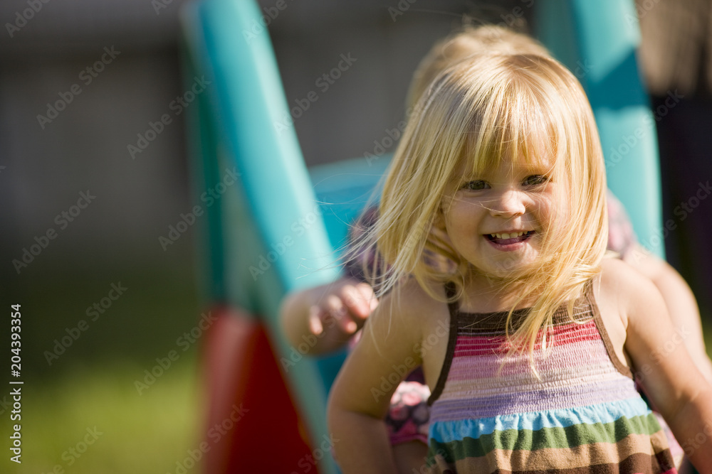 Little girl sliding down slide with baby sister Little girl sliding down slide with baby sister