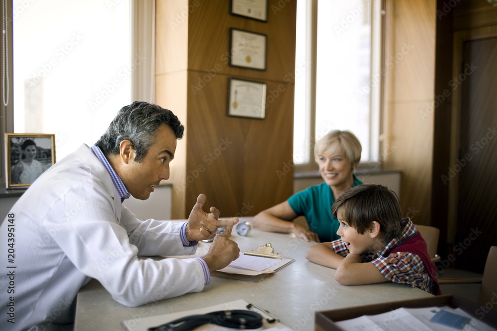 Middle aged doctor talking to a young boy and his mother. Middle aged doctor talking to a young boy and his mother.