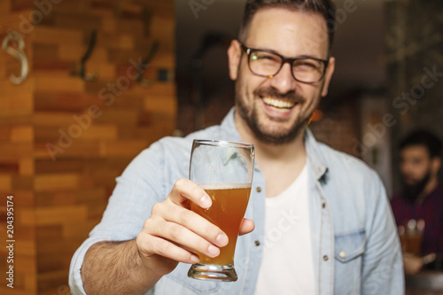 Young man holding glass of beer and smile
