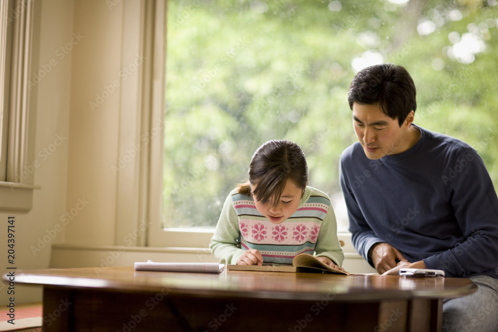 Girl reading book while father sitting besides her Girl reading book while father sitting besides her