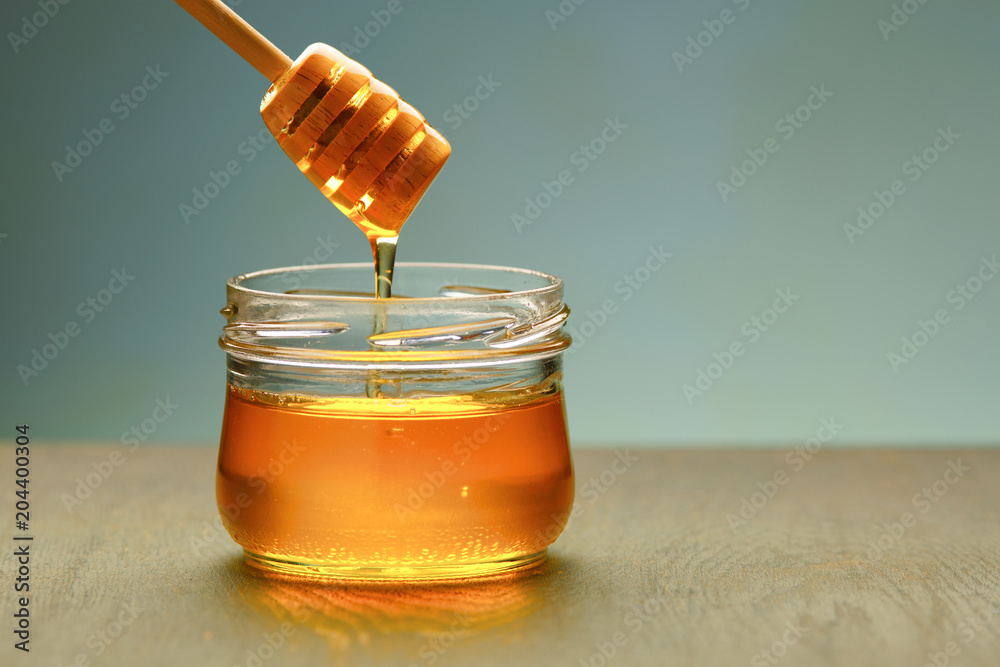 Honey background. Sweet honey in the comb, glass jar. On wooden background. Honey background. Sweet honey in the comb, glass jar. On wooden background.