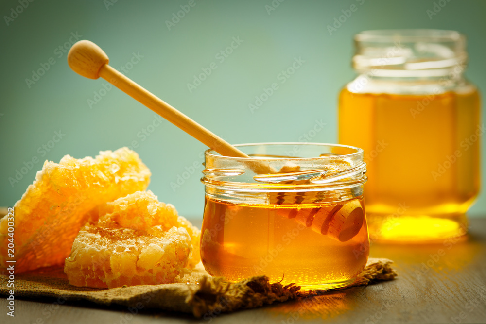 Honey background. Sweet honey in the comb, glass jar. On wooden background. Honey background. Sweet honey in the comb, glass jar. On wooden background.