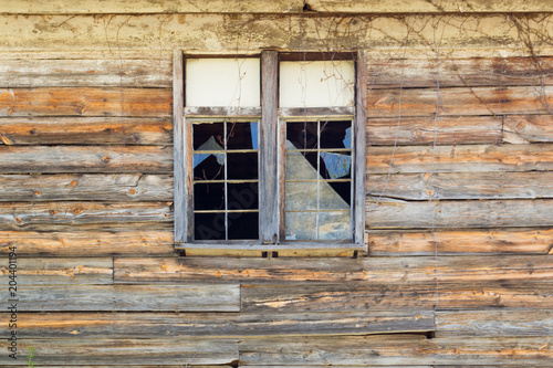 Old broken windows with shattered glass in a rustic wooden building.