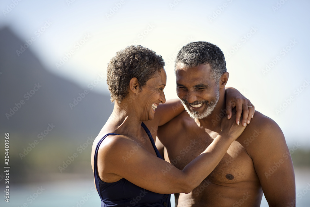 Mid adult couple standing with their arms around each other on a beach. Mid adult couple standing with their arms around each other on a beach.