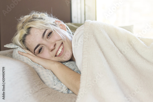 A beautiful happy content woman lying in bed smiling at camera.