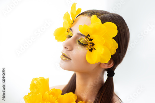 Beauty portrait of a brunette with extended eyelashes in the image of a tulip. On a white background