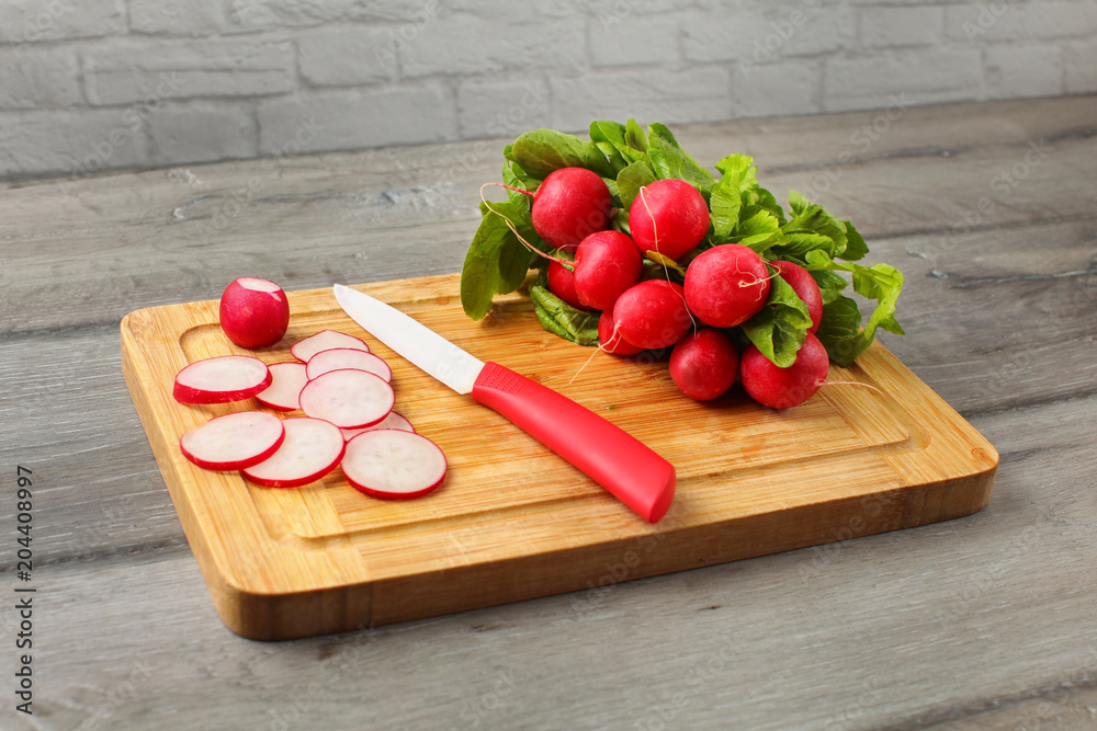 Fresh chopped radishes and a knife on a cutting board on a wooden