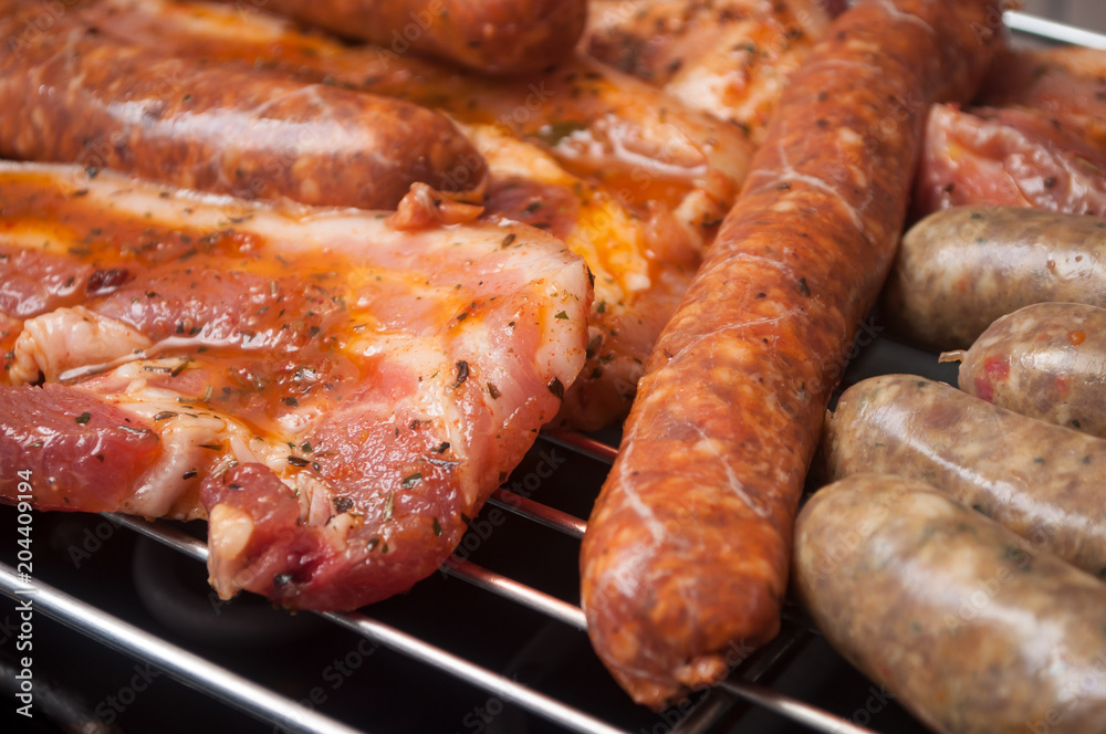 closeup of sausages and pork belly on the barbecue