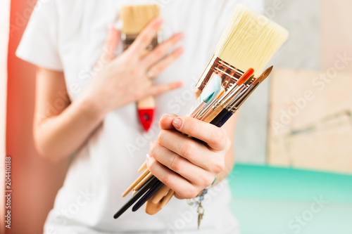 Closeup of woman holding painting brushes in her hand, selective shallow focus