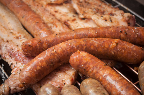 closeup of sausages and pork belly on the barbecue