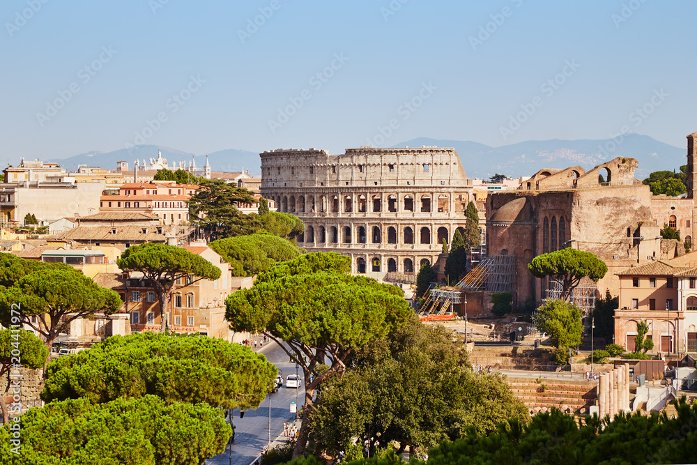 Panoramic shot of Rome cityscape with beautiful ancient Coliseum in landscape under blue sky.