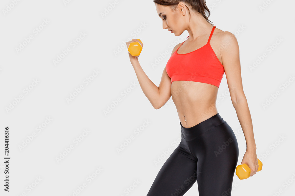 Young girl with a beautiful figure doing an exercise with dumbbells