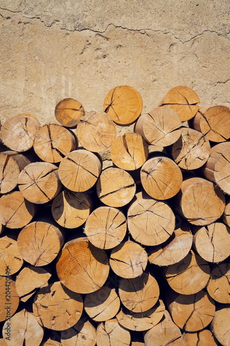 Pile of worked wooden roundish clear beautiful logs  stacked firewood background  view at saw cut  sunny day
