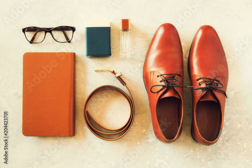 Men's accessories and shoes on gray background. Flat lay of elegant belt, glasses, parfume, notebook. Stylish set and fashion concept for man.