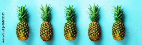 Bright pineapple pattern for minimal style. Top View. Pop art design, creative concept. Copy Space. Fresh pineapples on blue background. © jchizhe