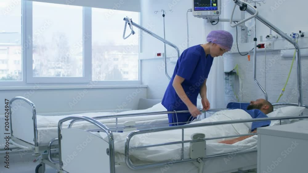 In the Hospital Medical Ward Nurse Takes Care of a Patient Lying in Bed. Clean Modern Hospital with Friendly and Professional Staff. Shot on RED EPIC-W 8K Helium Cinema Camera. In the Hospital Medical Ward Nurse Takes Care of a Patient Lying in Bed. Clean Modern Hospital with Friendly and Professional Staff. Shot on RED EPIC-W 8K Helium Cinema Camera.