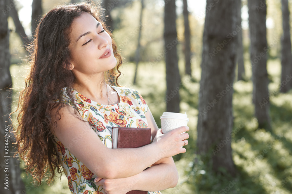 Naklejka premium beautiful girl in the forest, bright sunlight around, green grass and trees