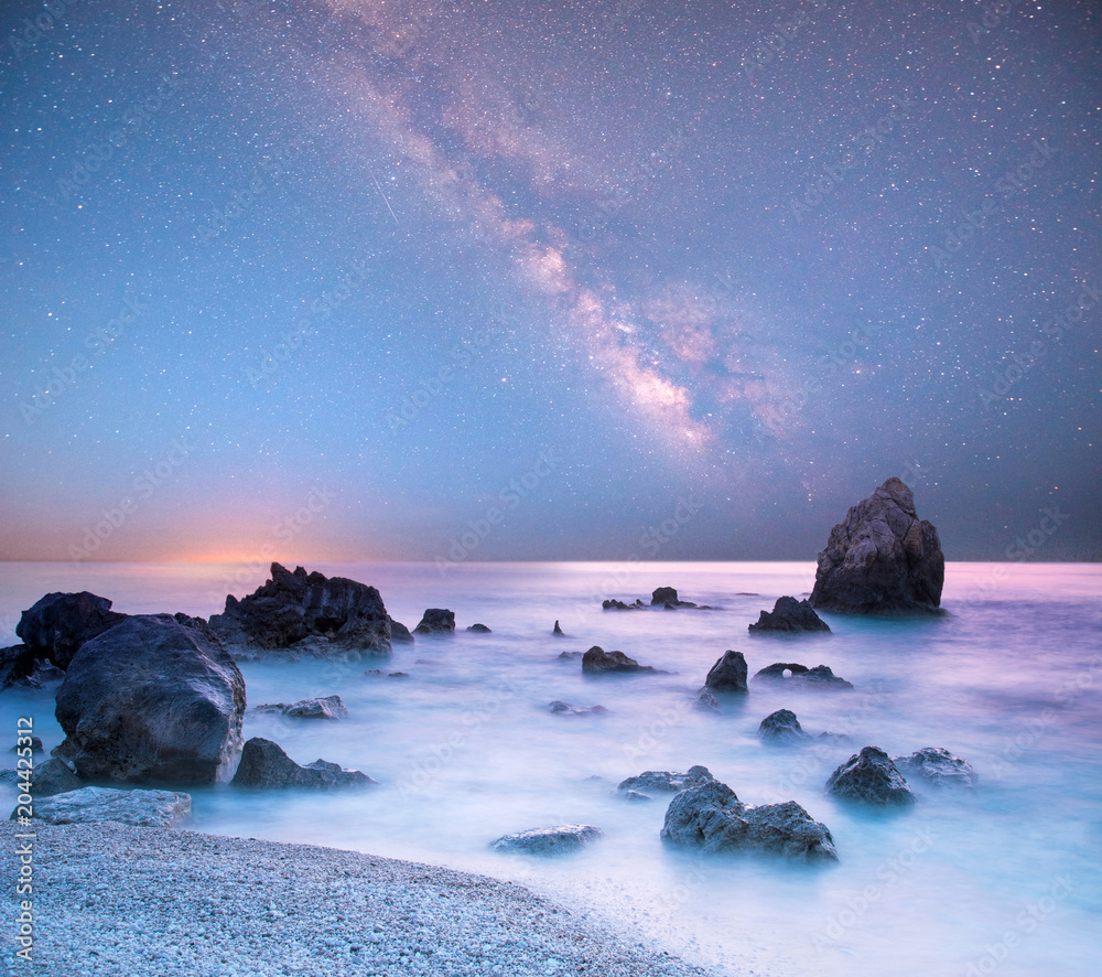 magical mystical beautiful charming landscape with waves and stones in the middle of the sea on the coast against the background of the stars and the Milky Way.