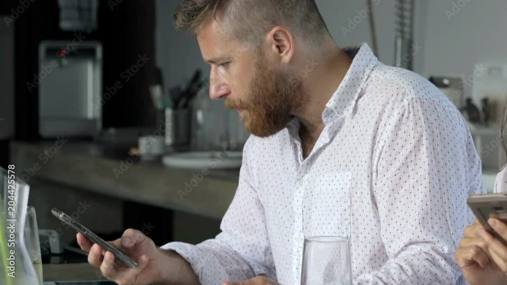 Couple using smartphones and eating meal in kitchen at home
Couple using smartphones and eating meal in kitchen at home