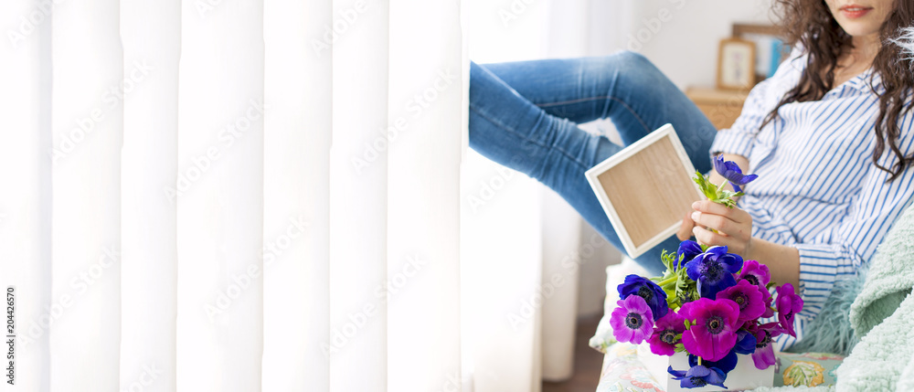 Woman with a bouquet of flowers in the living room by the window. Blue flowers. Romantic aftermarket for the beloved. Banner and space for text Woman with a bouquet of flowers in the living room by the window. Blue flowers. Romantic aftermarket for the beloved. Banner and space for text