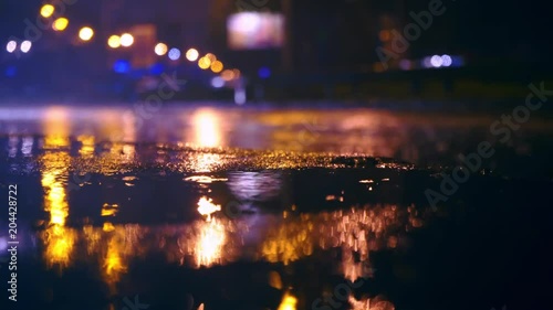 Cars drive into large puddles on the night road in the city, spray puddles scatter from under the wheels of the car