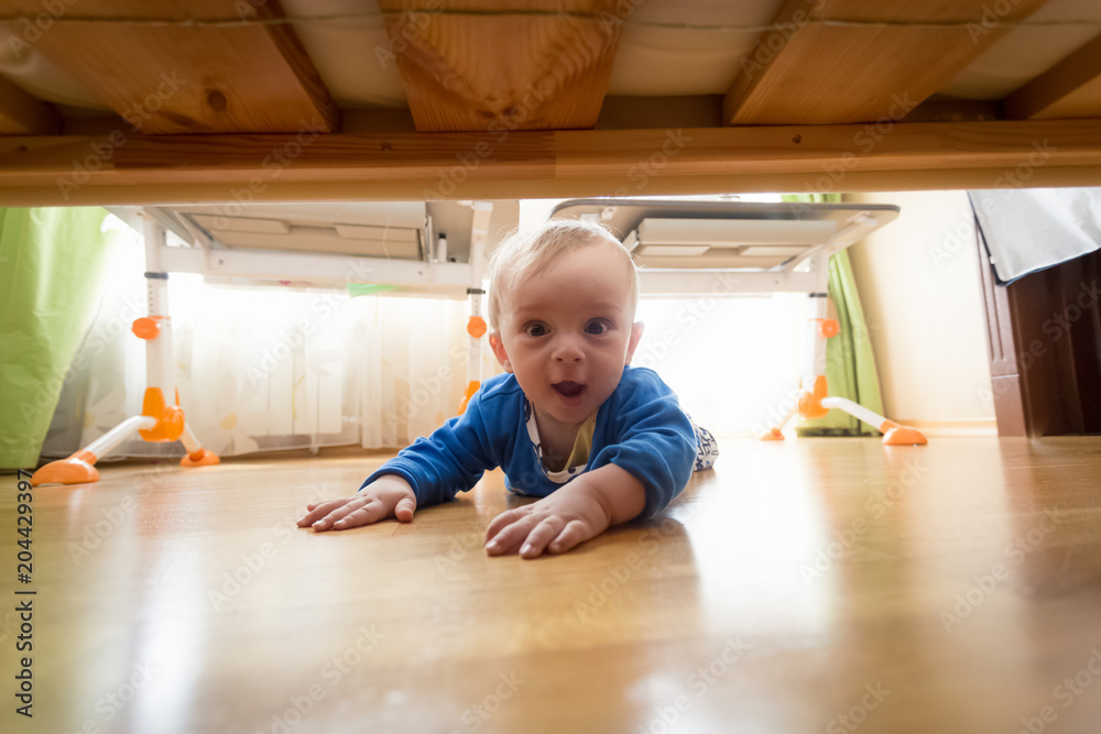 Funny portrait of amazed toddler boy lying on floor and looking under the bed Funny portrait of amazed toddler boy lying on floor and looking under the bed
