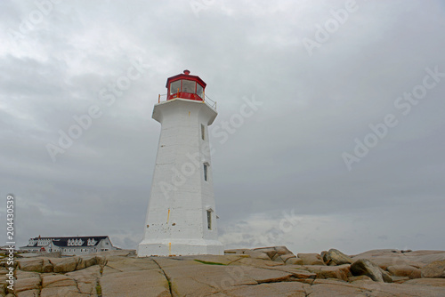 Peggys Point Lighthouse in cloudy in historic Peggy`s Cove, Nova Scotia, Canada. The lighthouse was built in 1914 and is regarded as the most famous landmark in Atlantic Canada. photo