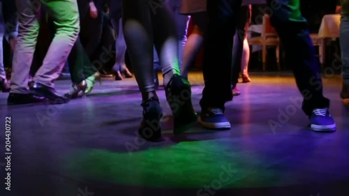The guy and the girl skillfully dance in the party in the style of bachata. Night, indoors, party, disco lights on the dance floor a lot of people