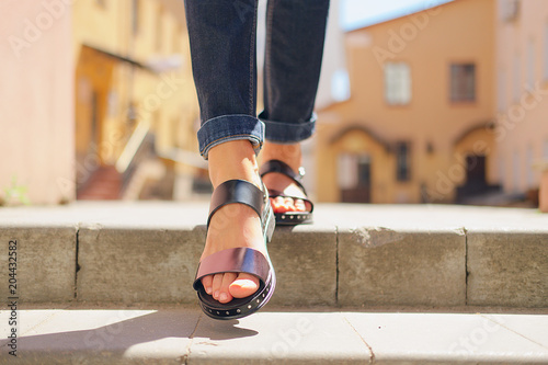 Female legs in sandals descending the stairs in the city photo