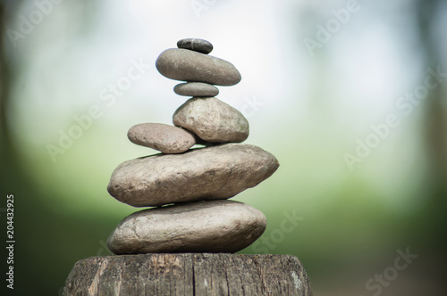 Photography closeup of stones balance on wooden fence on green blurred background