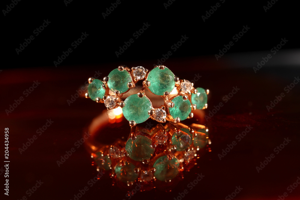 Women's ring made of gold with emeralds close-up Women's ring made of gold with emeralds close-up