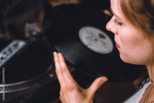 young woman putting on a vinyl record at home photo