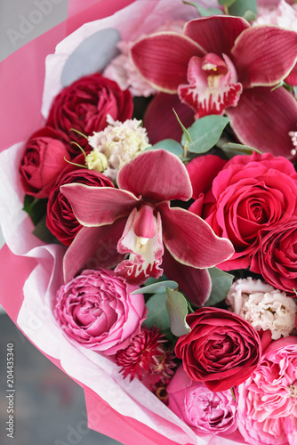 Bright red bouquet of beautiful flowers on wooden table. Floristry concept. Spring colors. the work of the florist at a flower shop. Vertical photo