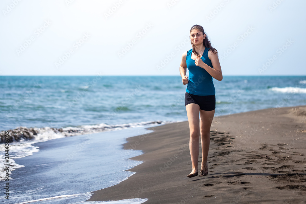 Beautiful sportive girl running along beautiful sandy beach, healthy lifestyle Beautiful sportive girl running along beautiful sandy beach, healthy lifestyle