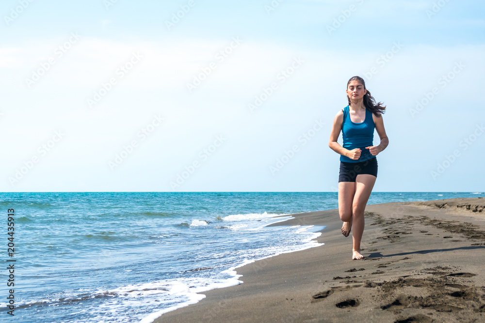 Beautiful sportive girl running along beautiful sandy beach, healthy lifestyle Beautiful sportive girl running along beautiful sandy beach, healthy lifestyle