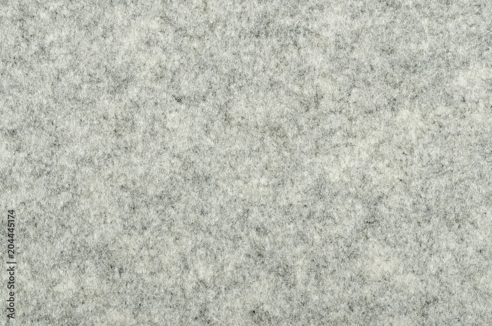 Fototapeta premium Gray felt surface. Textile material, made of matted synthetic fibers. White, gray and black acrylic pressed together. Fabric pattern. Background. Photography from above.