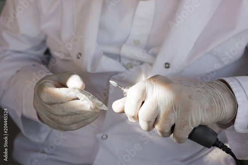 Dentist with latex gloves holding mouth guard in one hand and polish tool on another photo