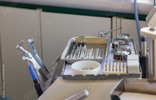 Dental instruments on silver tray including calculus plaque remover, tooth scraper and mirror set at clinic. Medical care concept