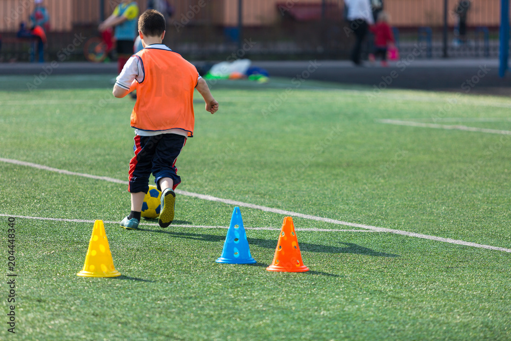 Obraz premium boys football players practice dribbling, kickson soccer training on the field in the summer