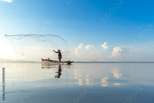 Принти на полотні Fisherman action when fishing net on lake in the sunshine morning, beautiful blue sky background